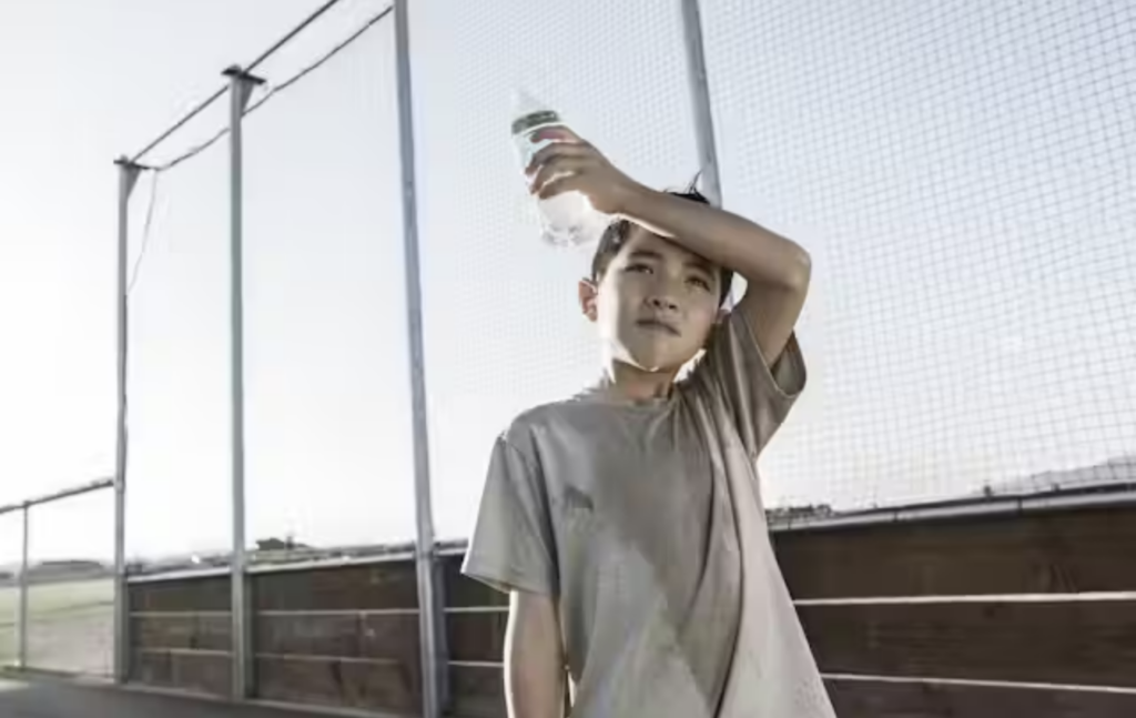 Kid holds water bottle in summer heat